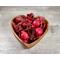 Handcrafted, heart-shaped wooden bowl filled with red apple cinnamon potpourri on a grey wood-grain surface